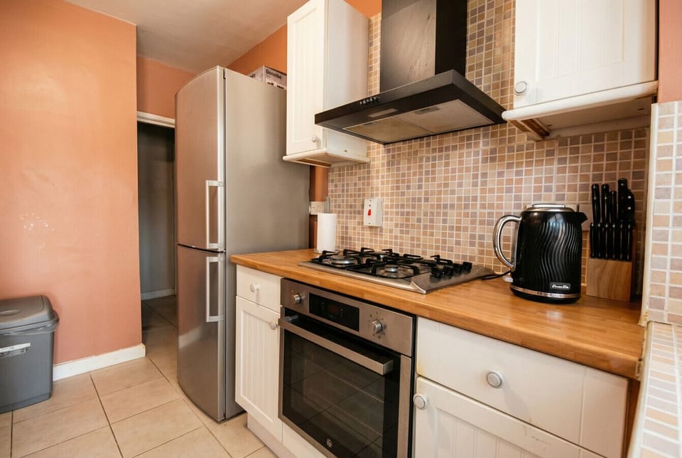 Fully equipped kitchen with gas hob, oven, and a large fridge freezer for home cooking.