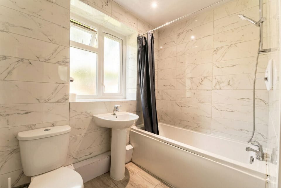 Marble-tiled bathroom with a full bath, overhead shower, and fresh towels provided.