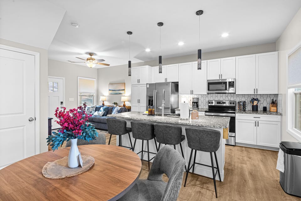 A bright, open-concept kitchen designed for gathering—featuring sleek finishes, ample seating, and seamless flow into dining and living spaces. Perfect for shared meals, morning coffee, and relaxed evenings in.