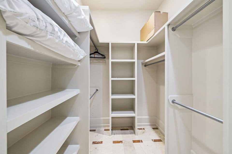 Store all your belongings in this spacious walk-in closet with custom shelving and hanging rods for organized comfort.