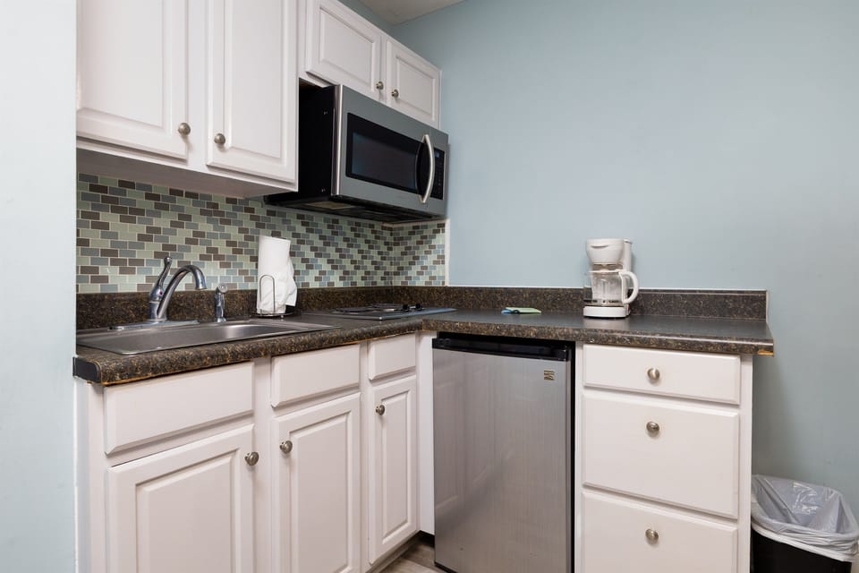 Bright and well-equipped kitchenette with microwave, mini fridge, coffee maker, and a cozy dining table, perfect for easy meals and relaxed mornings