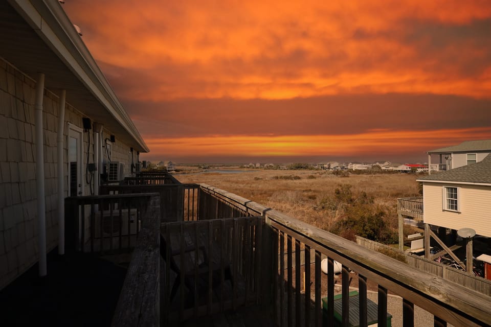 Golden-hour skies and coastal marshland create a stunning sunset backdrop from your balcony