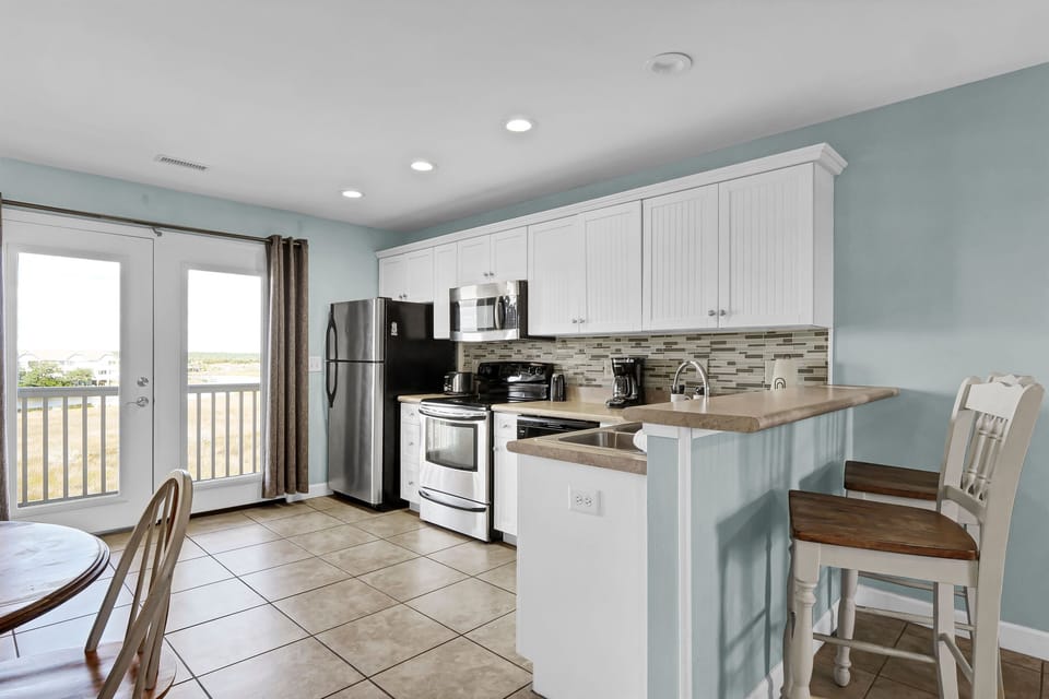 Open-concept kitchen featuring a breakfast bar with seating, stainless steel appliances, and plenty of counter space for easy meals