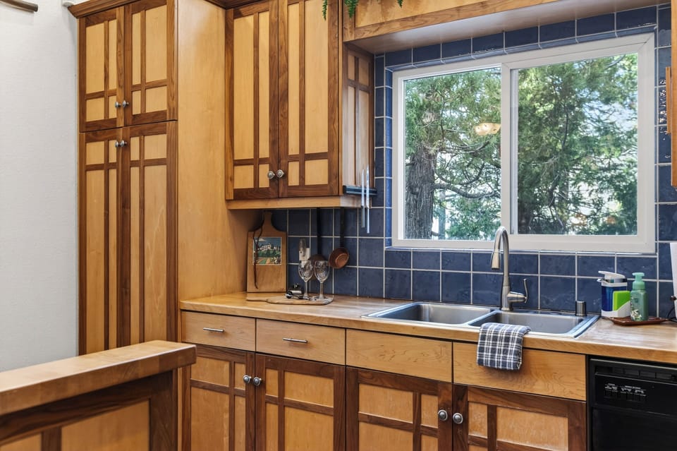A bright, inviting kitchen with warm wood cabinetry, vaulted ceilings, and a spacious breakfast bar—perfect for morning coffee, shared meals, and easy entertaining.