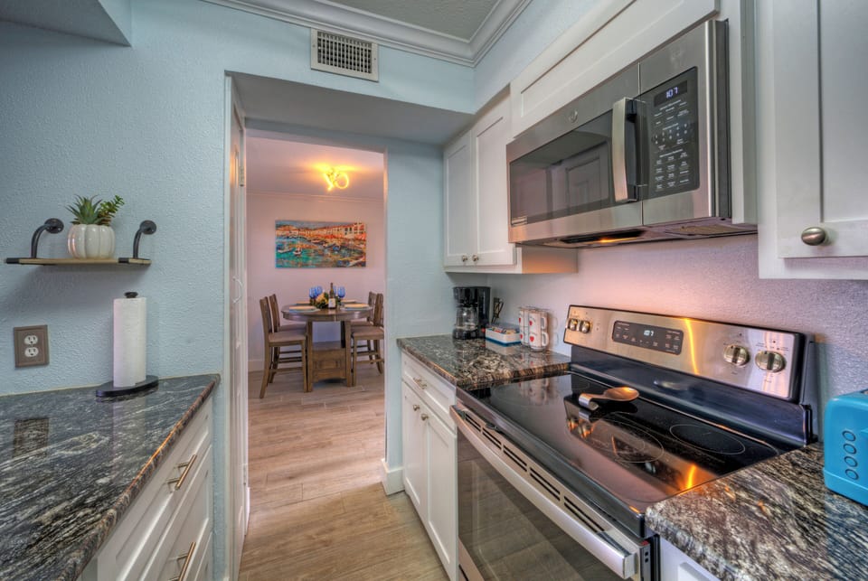 Modern galley kitchen with granite countertops and stainless steel appliances.