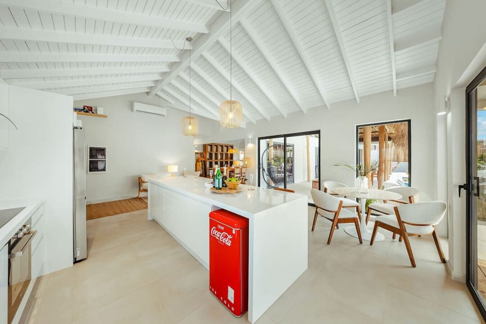 A sleek, modern kitchen with a massive island and a retro drink fridge—the perfect hub for prepping snacks or gathering for a cold beverage.
