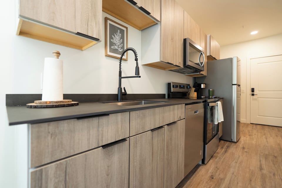 Your modern kitchen features sleek wood cabinets, stainless steel appliances, and dark countertops—perfect for preparing meals during your stay.