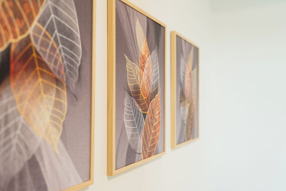 Warm autumn-themed artwork adorns your walls, creating a cozy atmosphere with golden leaf motifs in elegant frames.