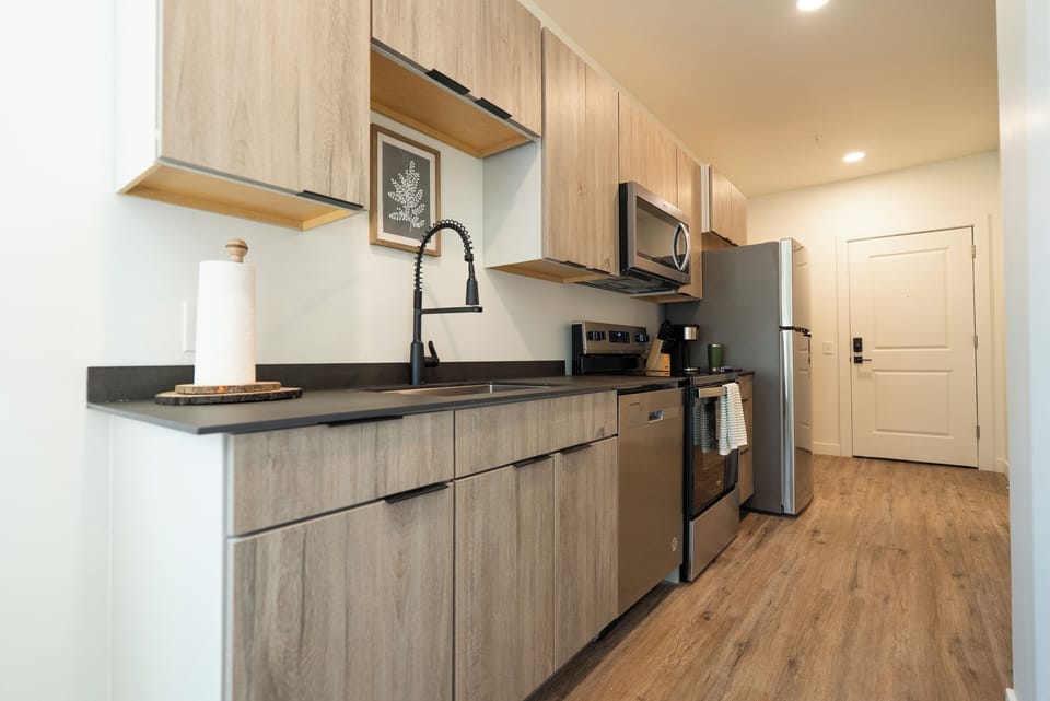 Your modern kitchen features sleek wood cabinetry, stainless steel appliances, and dark countertops - perfect for preparing meals during your stay.