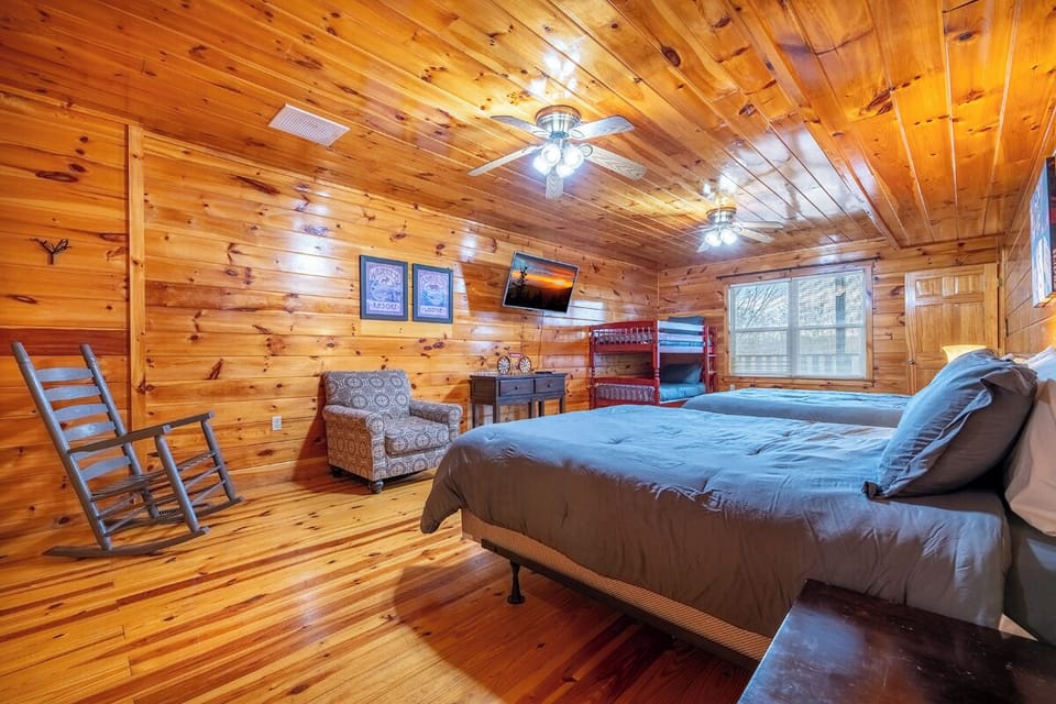 Unwind in your cozy cabin bedroom with warm wood walls, comfortable beds, and rustic charm that makes every night feel like a mountain retreat.
