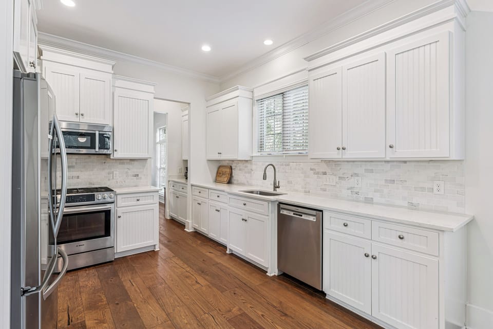 You'll love preparing meals in this bright, fully-equipped kitchen with premium appliances, elegant white cabinetry, and beautiful marble backsplash.