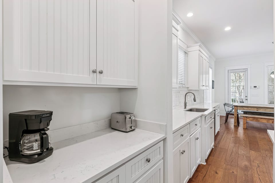 Your bright, fully-equipped kitchen features pristine white cabinetry and marble countertops, perfect for brewing morning coffee or preparing memorable meals.