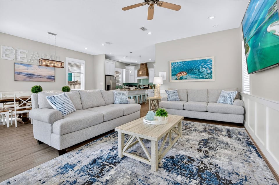 1st Floor - Spacious open-concept living room with comfortable lounge seating and an oversized 85” 4K Smart TV—perfect for movie nights, game days, and relaxing after the beach. Designed for large groups to gather, connect, and unwind in style.