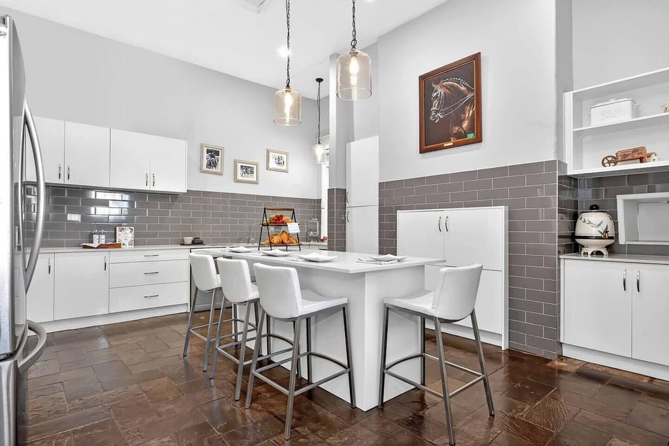 The fully-equipped kitchen offers modern appliances and generous bench space with dining stools — beautifully updated while complementing the home’s vintage charm.