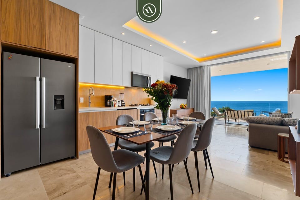 Gather in the stylish open-concept living space featuring a fully equipped kitchen, elegant dining area, and ocean views beyond.