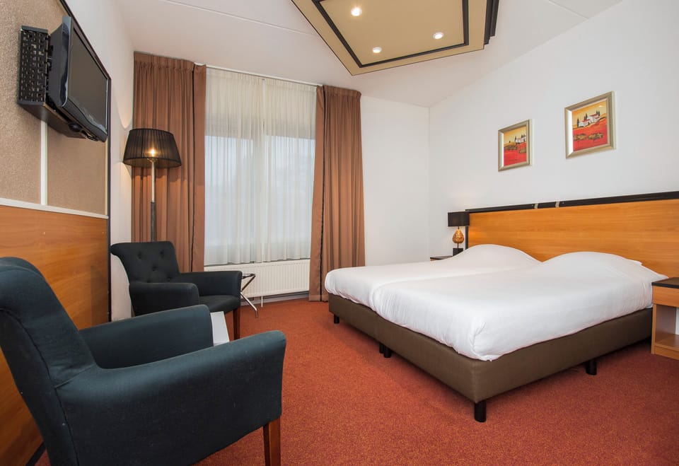 Relax in a spacious bedroom with cozy seating and warm lighting.