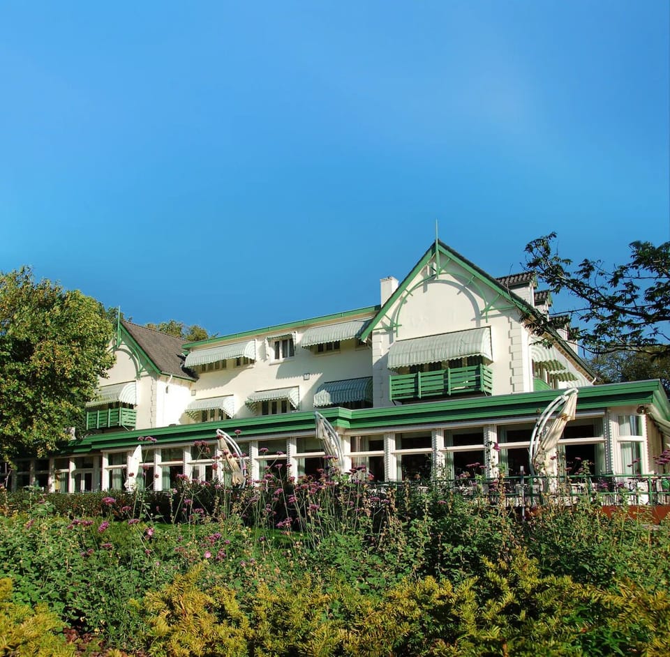 Arrive to charming green-trimmed elegance framed by gardens