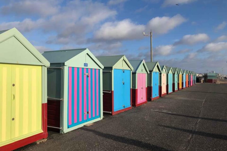 A row of colorful beach huts lining the seafront walk from Hove into Brighton.