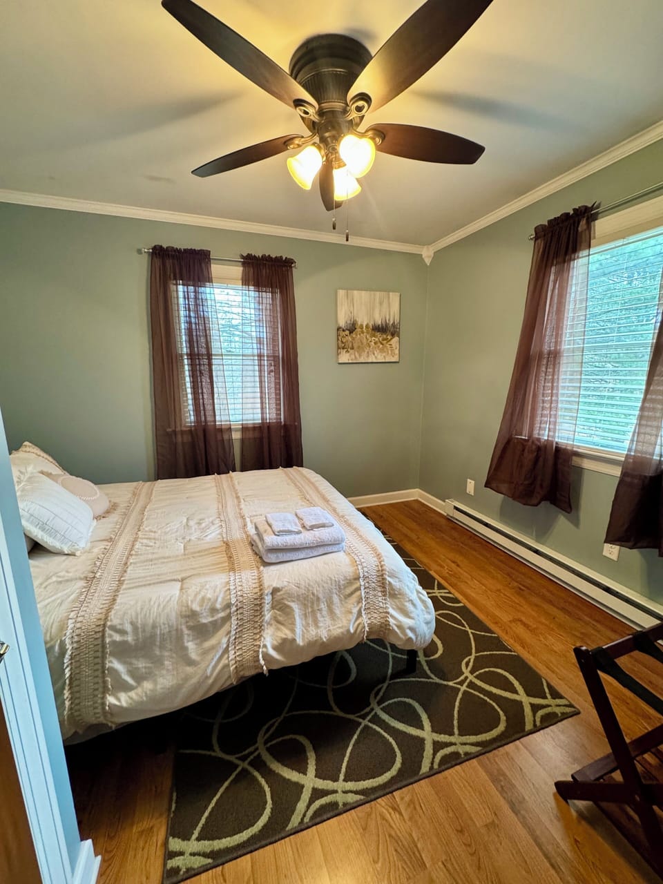 Relaxing queen bedroom with plush bedding, hardwood floors, and ceiling fan.