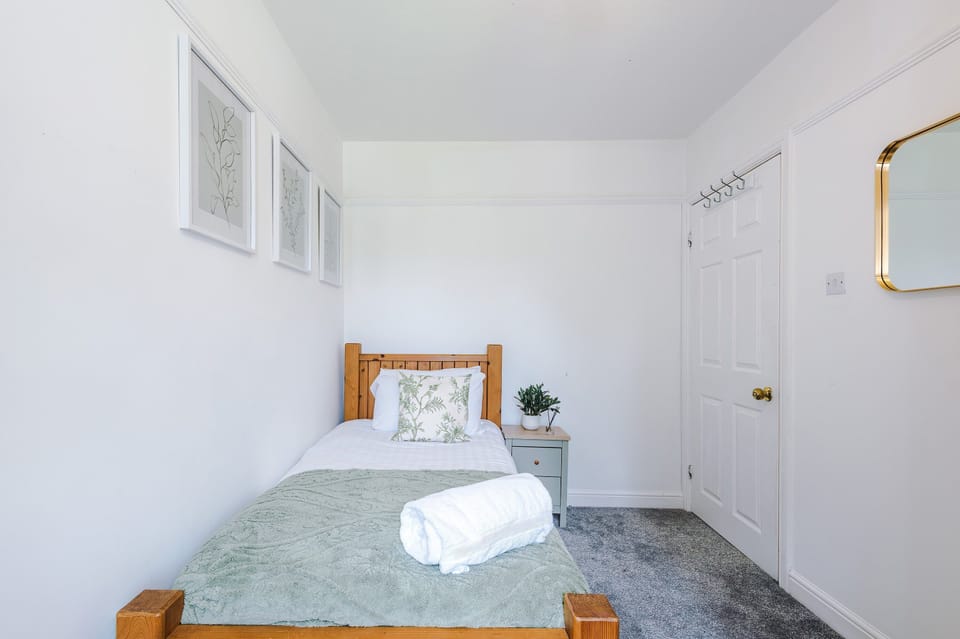 Single bedroom with a pine bed, bedside table and coat hooks on the back of the door
