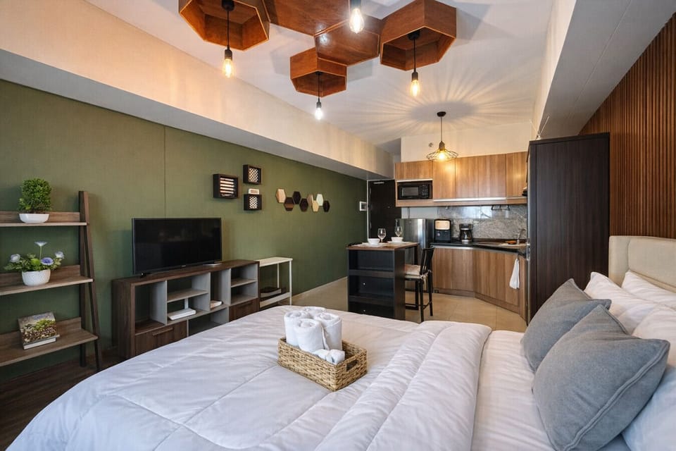 Bright open-concept layout featuring hotel-style bedding, entertainment setup, and complete kitchen amenities.