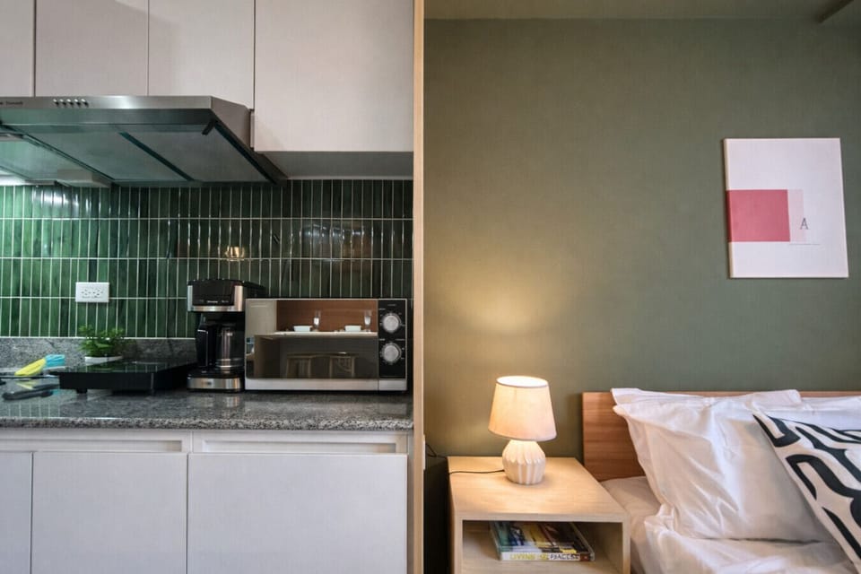 Comfort meets convenience—fully equipped kitchenette beside a cozy bed with warm ambient lighting for a relaxing stay.