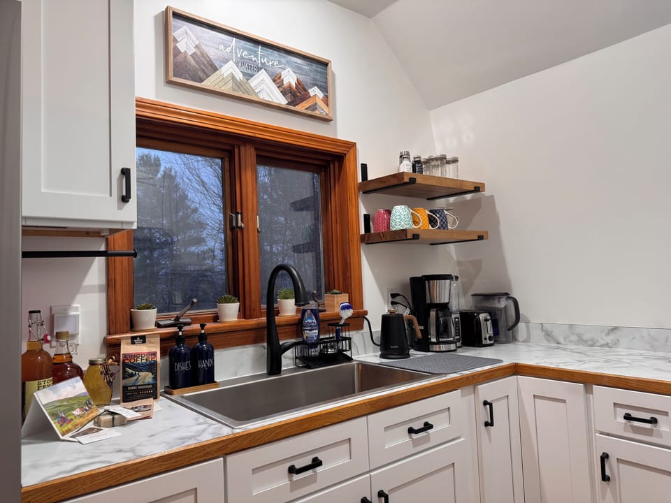 Brand-new kitchen with gas range, quality cookware, and coffee station.