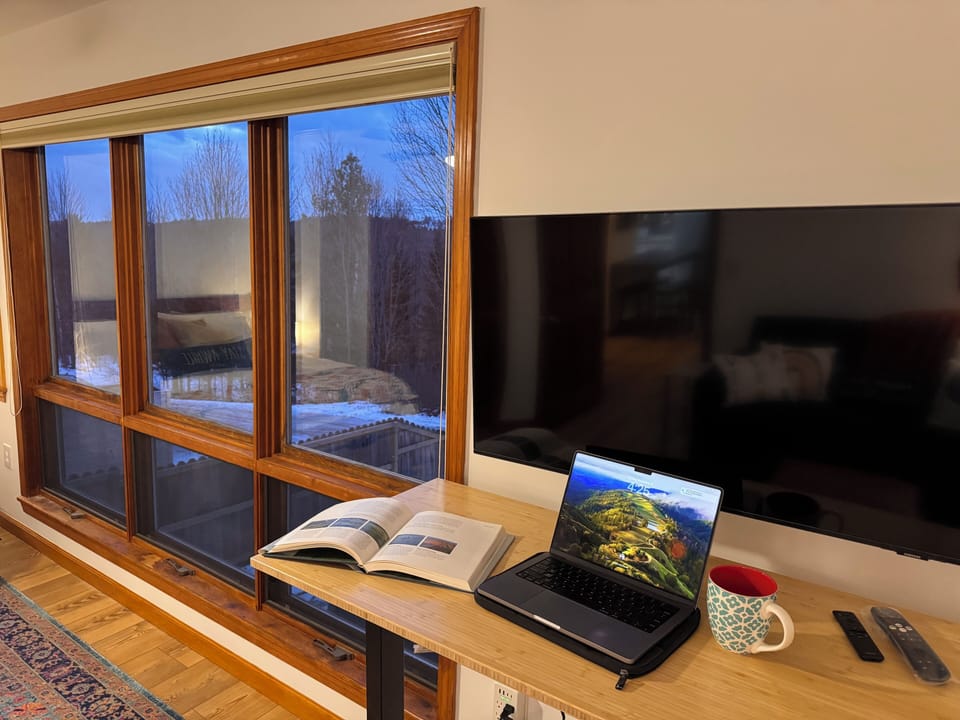 Dedicated workspace with adjustable standing desk. Large HD monitor doubles as a
