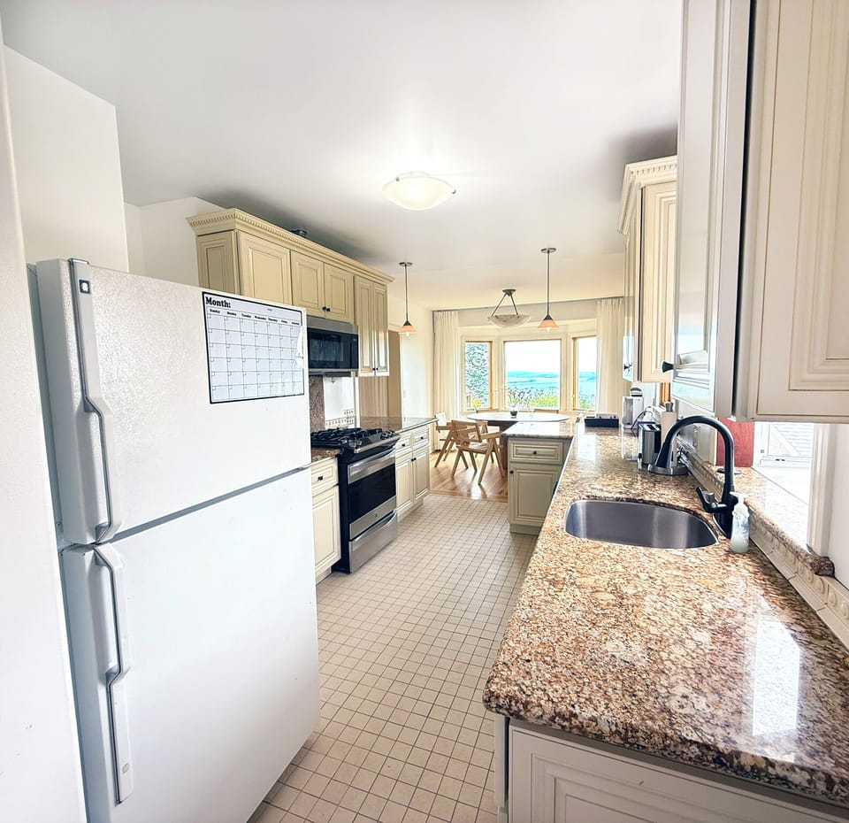 Spacious galley kitchen fully equipped for your stay—complete with granite counters, double ovens, and views stretching to the Bay.