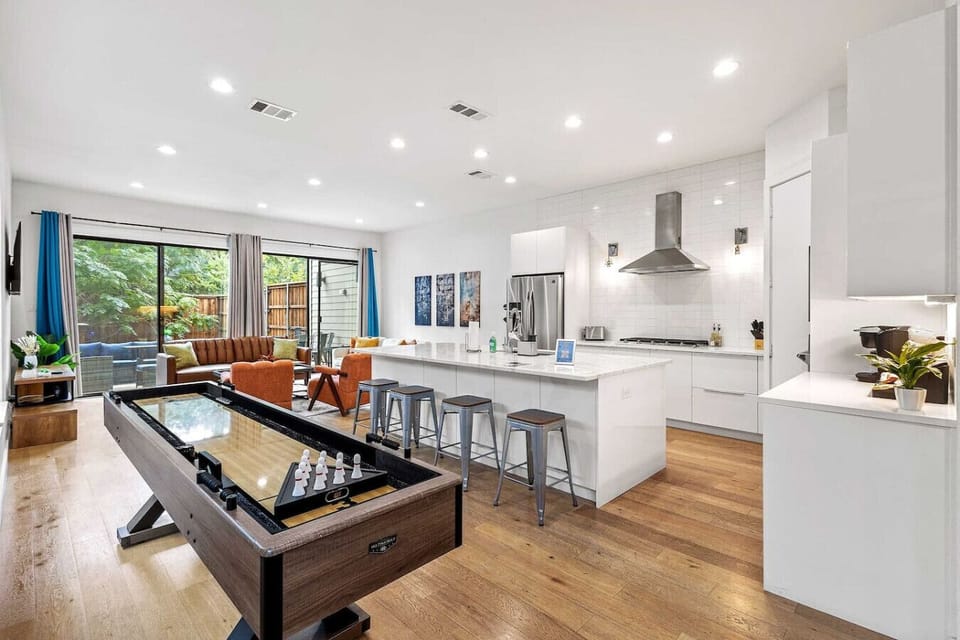 Spacious open-concept game and living area featuring a sleek shuffleboard table perfect for friendly competition and entertainment.