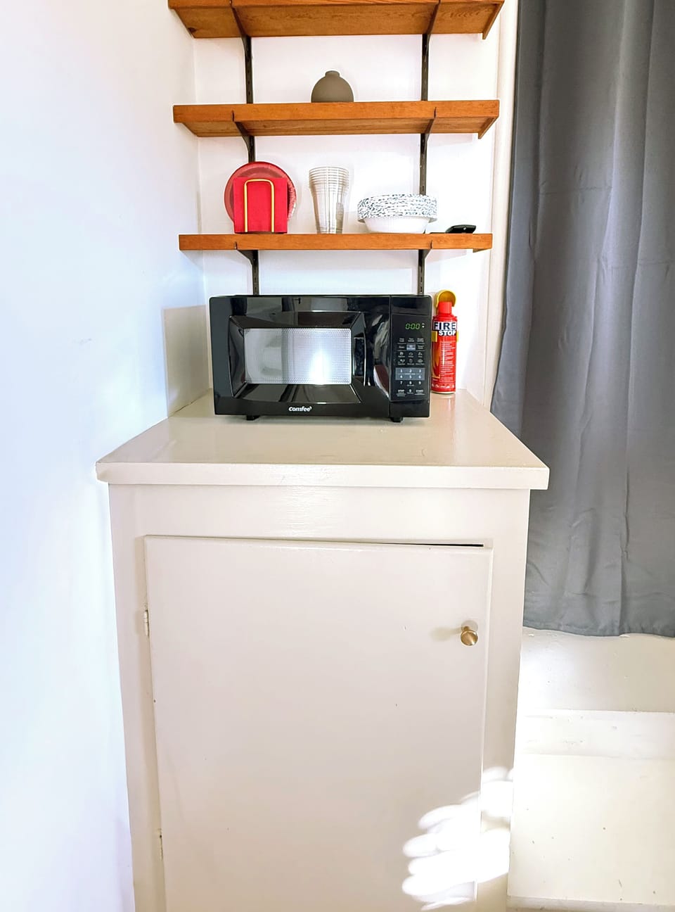 Convenient food prep area with microwave, dishes, and essentials for light cooking.