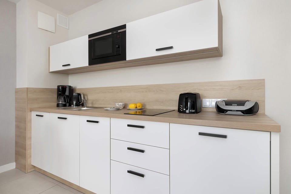 A close-up reveals the efficient layout of the kitchenette drawers and cupboards under a bright countertop. Subtle under-cabinet lighting illuminates the workspace, making meal preparation easy and pleasant.