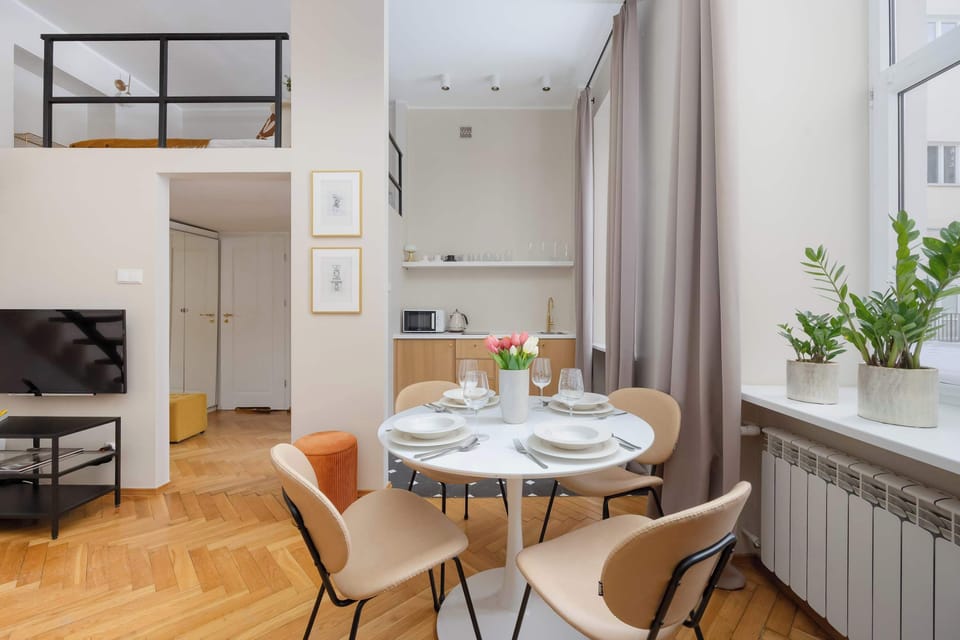 Open-plan studio with a dining table, living space and a view of the stairs connecting to the upper level.