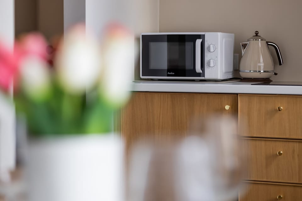 Kitchenette detail with wooden cabinetry and fresh flowers creating a welcoming atmosphere.