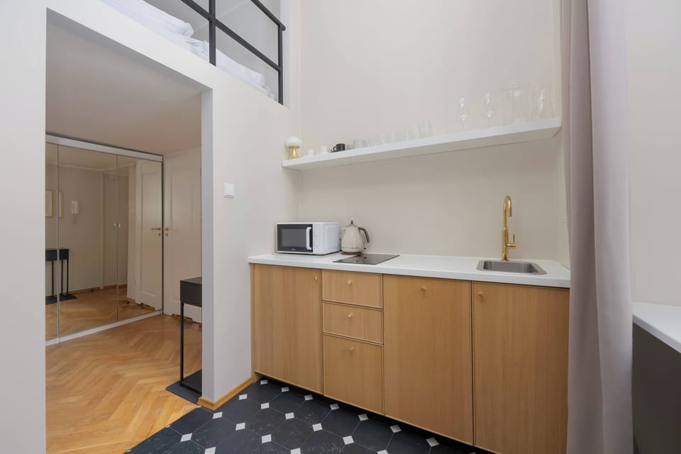 Compact kitchenette with wooden cabinets, open shelves and modern appliances.