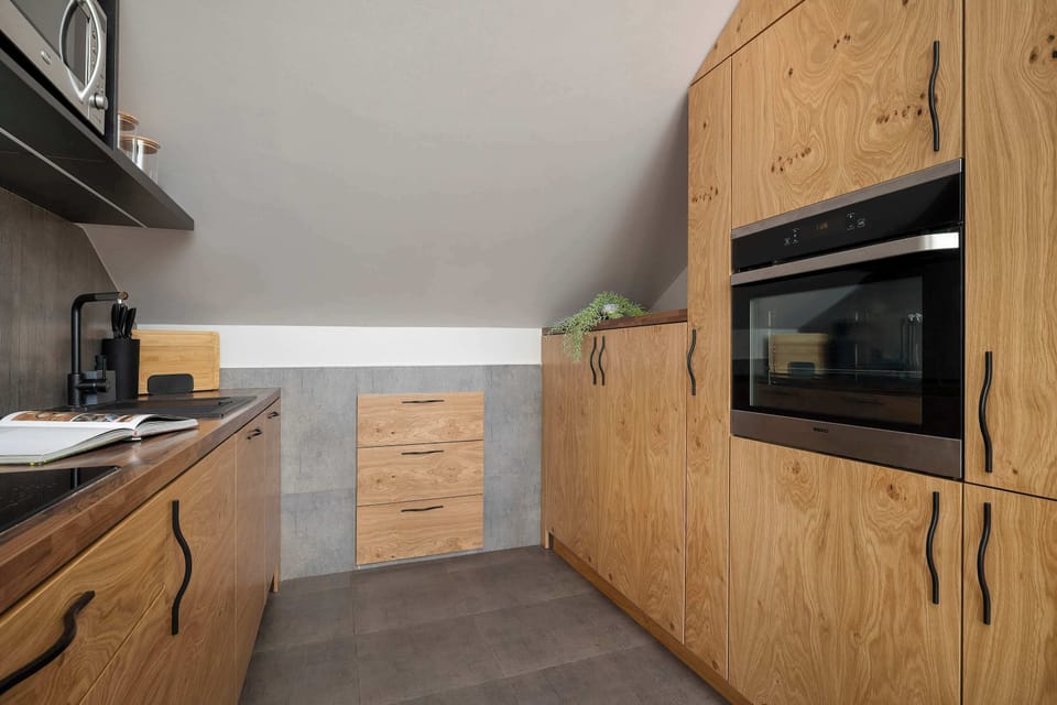 The kitchen area with a built-in oven and ample storage drawers. Light tiles and wooden textures create a warm atmosphere.