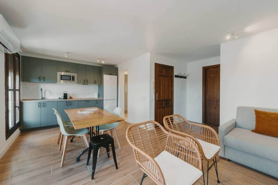 Salón comedor abierto a la cocina, con sillones de mimbre