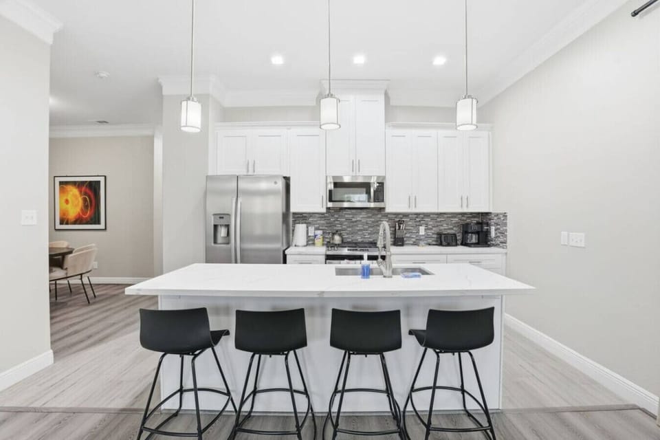Clean-lined kitchen with a spacious island, ample seating, and an open sightline into the dining area—designed for easy hosting and everyday use.