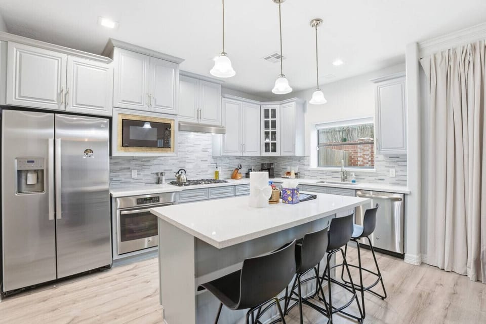 Modern kitchen with stainless appliances, quartz counters, and island seating—set up for easy meals, morning coffee, or group prep sessions.