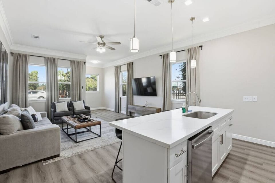 Open kitchen and living area with island seating, modern lighting, and a bright, airy layout made for easy living and gathering.