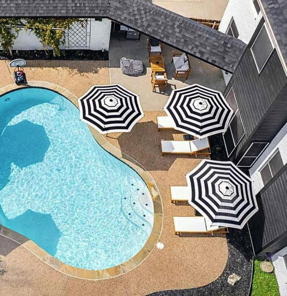 Private backyard oasis featuring a sparkling pool, sun loungers, and multiple shaded seating areas, perfect for relaxing and entertaining.