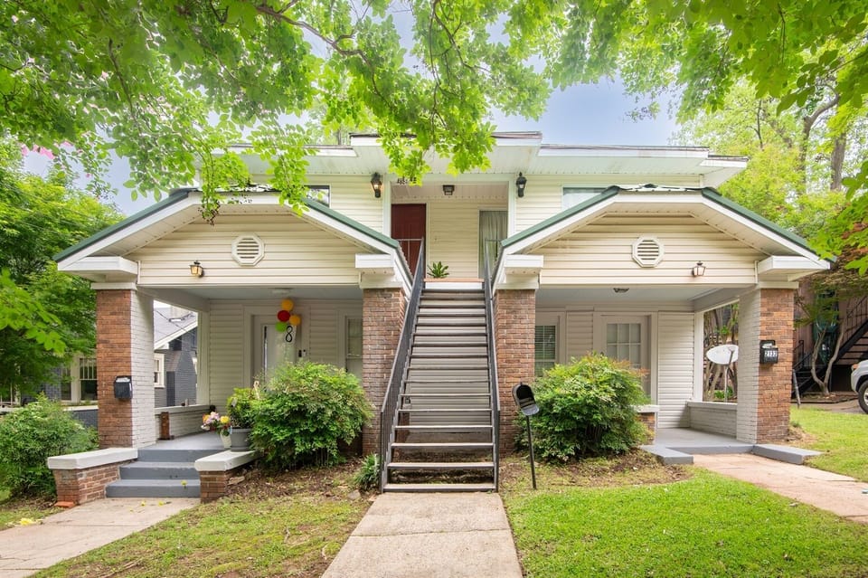 Charming exterior with inviting curb appeal – A cozy duplex-style home with covered front entry and a shared green lawn.