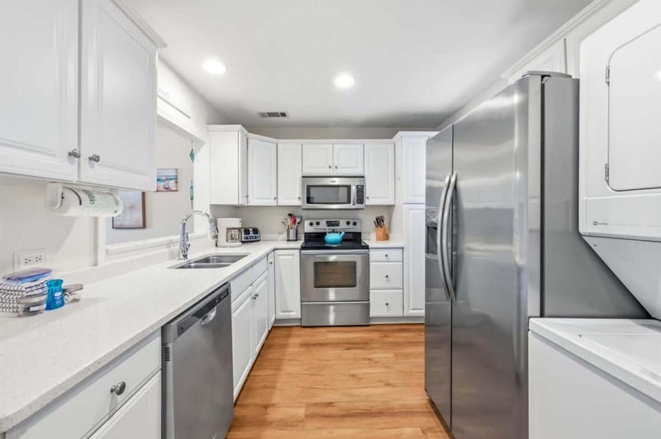 Modern, fully equipped kitchen with stainless appliances and stacked washer/dryer