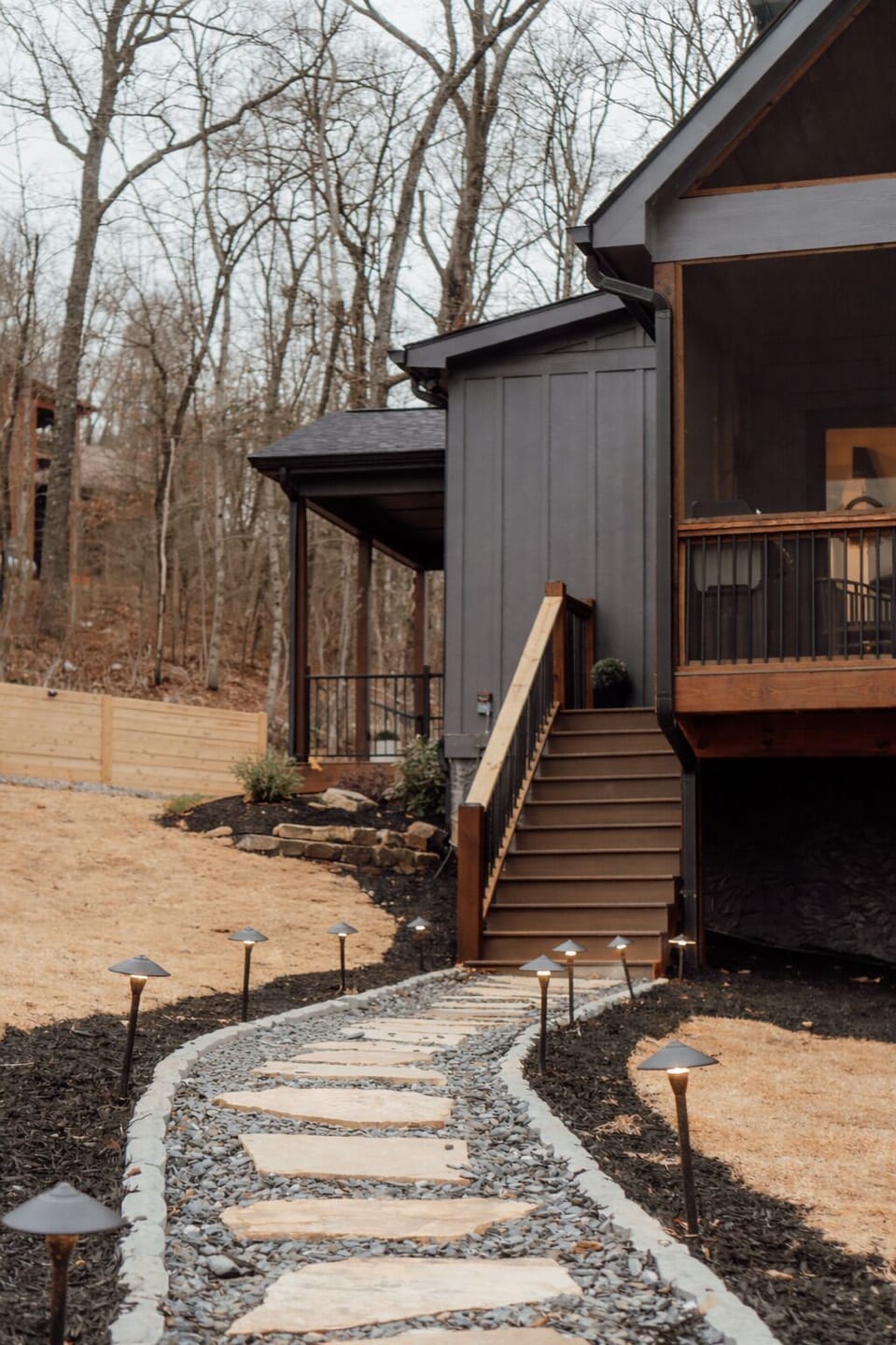 Modern cabin with lit stone path and cozy screened porch retreat