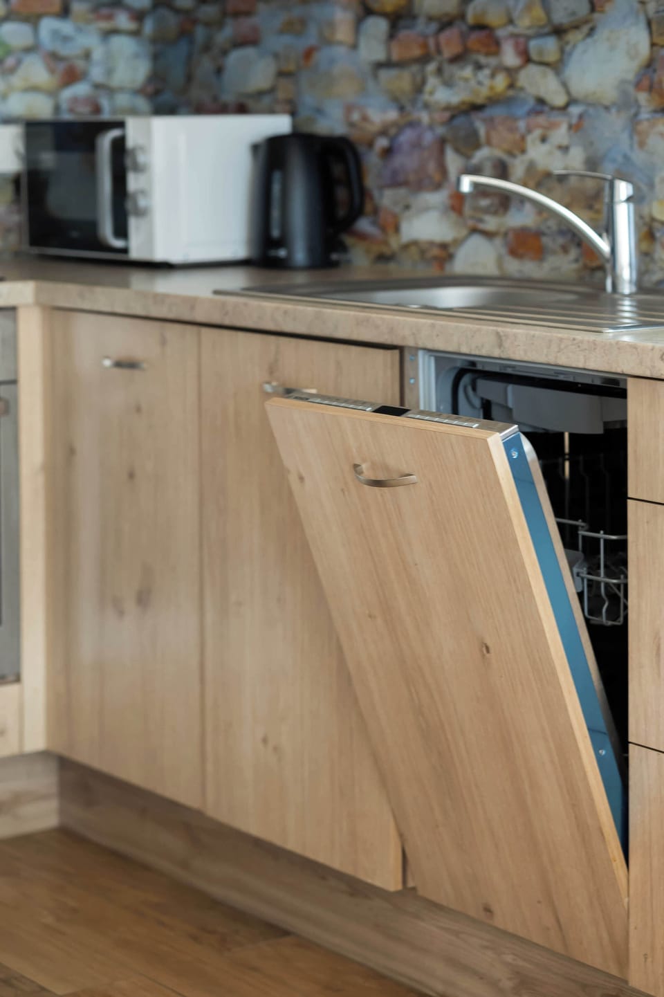 A detail of the kitchen furniture with a built-in dishwasher, which proves the high standard of equipment facilitating everyday functioning. Under-cabinet lighting adds a modern touch to the kitchen.