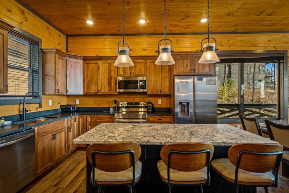 The fully equipped kitchen makes gathering easy with stainless steel appliances, warm wood cabinetry, and a spacious island with bar seating. Perfect for morning coffee quick snacks or full family dinners.
