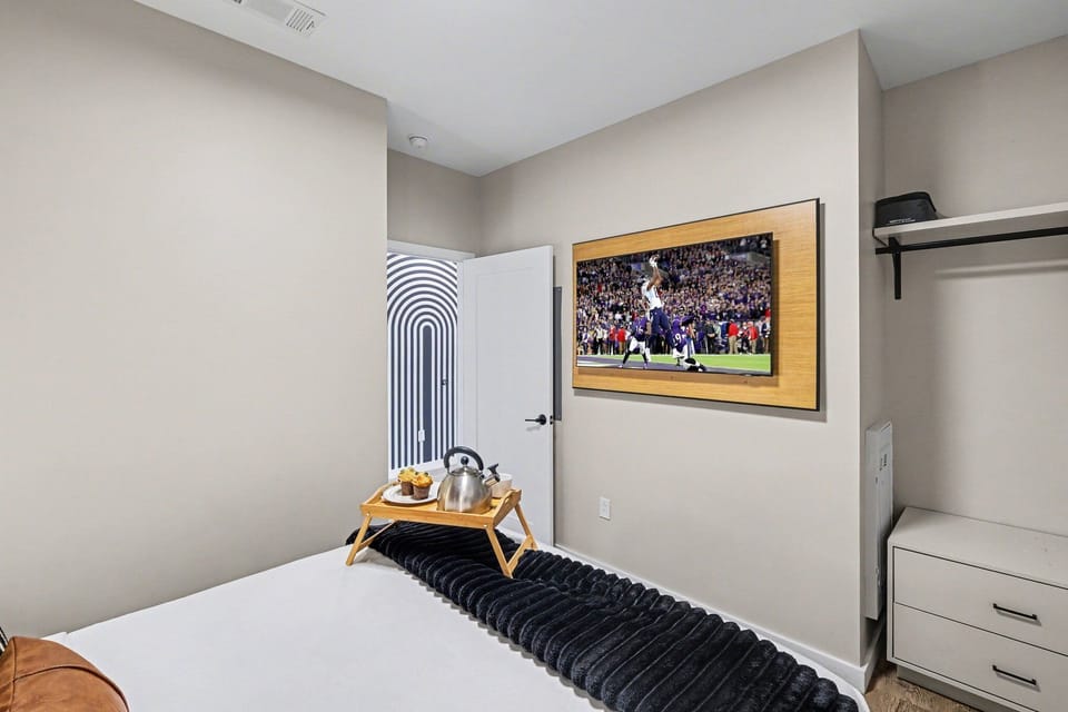 Unit 2: The primary bedroom features a plush Queen-sized bed with a wall-mounted smart TV and includes closet space to store your belongings.