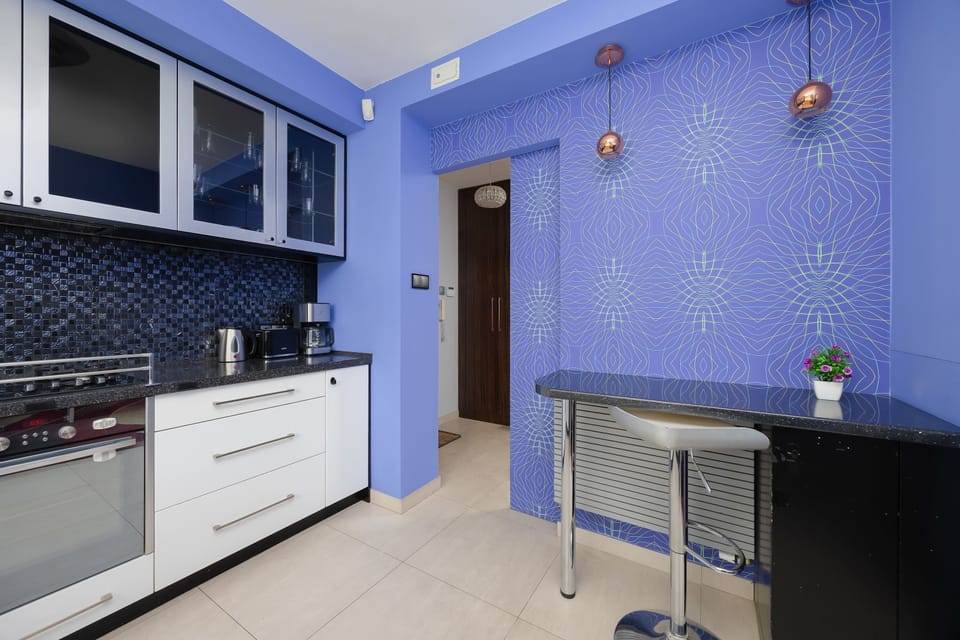 A compact blue-themed kitchen with built-in cabinets and a small breakfast bar. The design is practical and neatly organized.