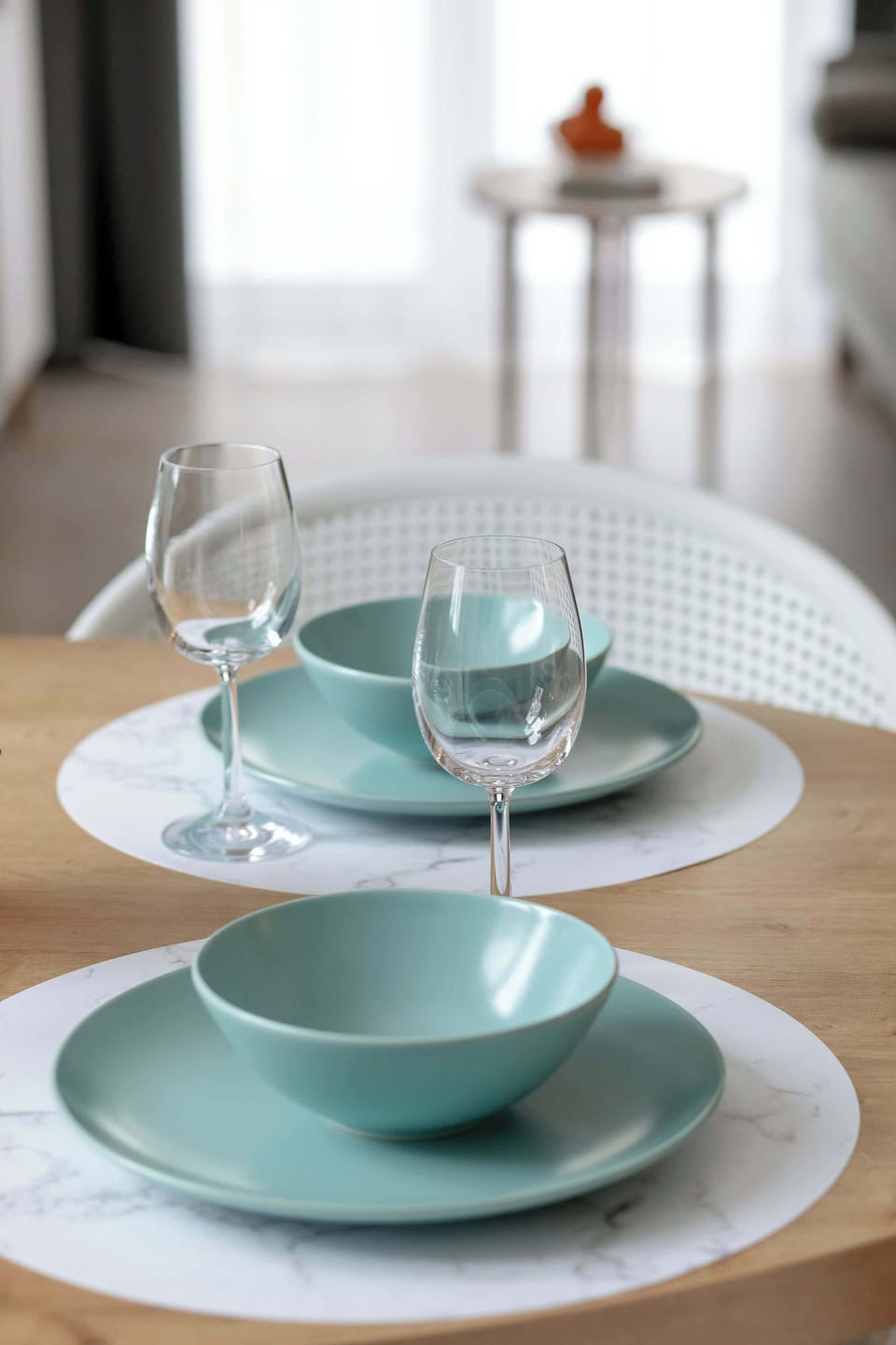 A minimalist table setting focuses on turquoise bowls and wine glasses, reflecting a high standard of hospitality.