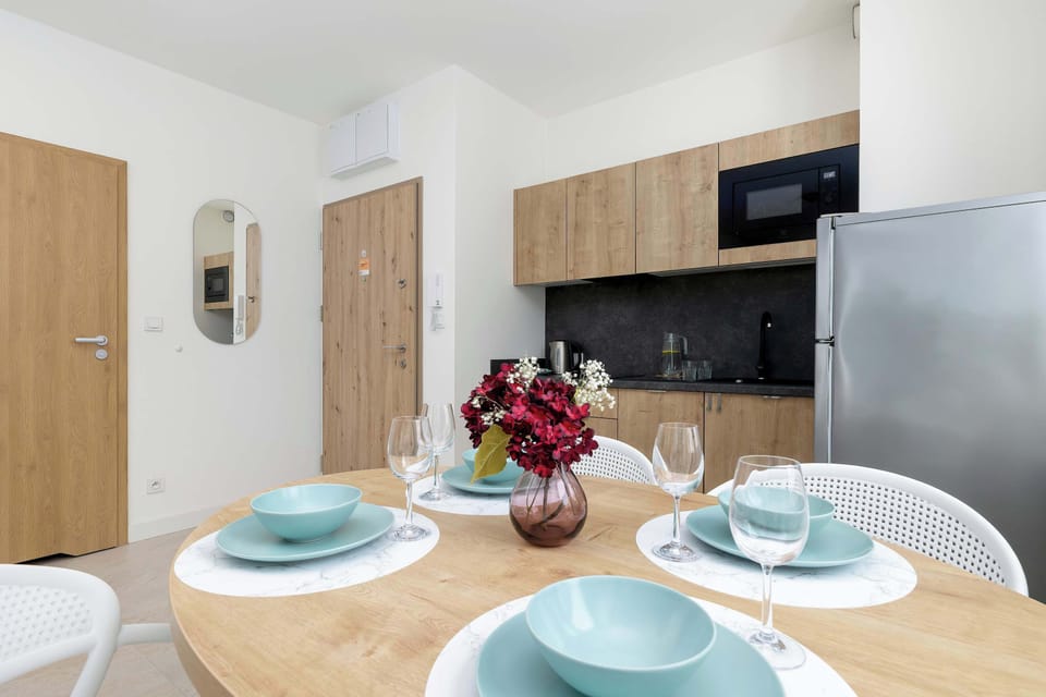 The dining table is elegantly set with blue tableware and a floral centerpiece, situated next to a large silver refrigerator.